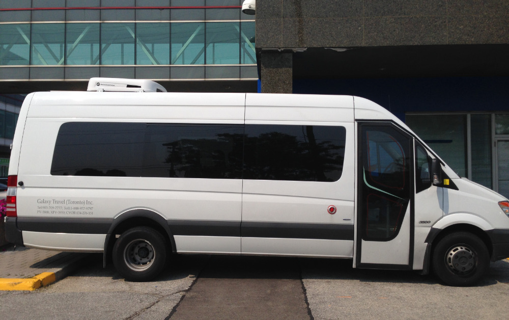 White 15 seater sprinter for rent outside the building