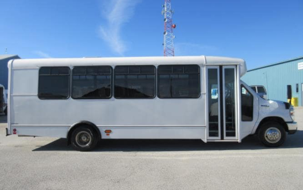 White 25 seater mini bus standing in front of tower