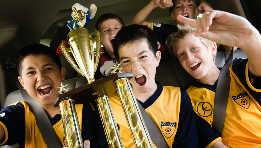 A group of boys wearing a soccer team shirts and holding a trophy
