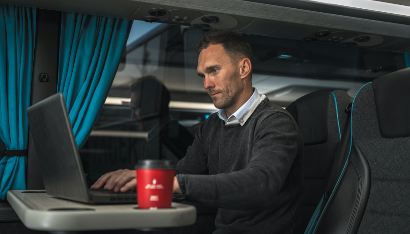 A business men comfortably working on his laptop inside a coach bus