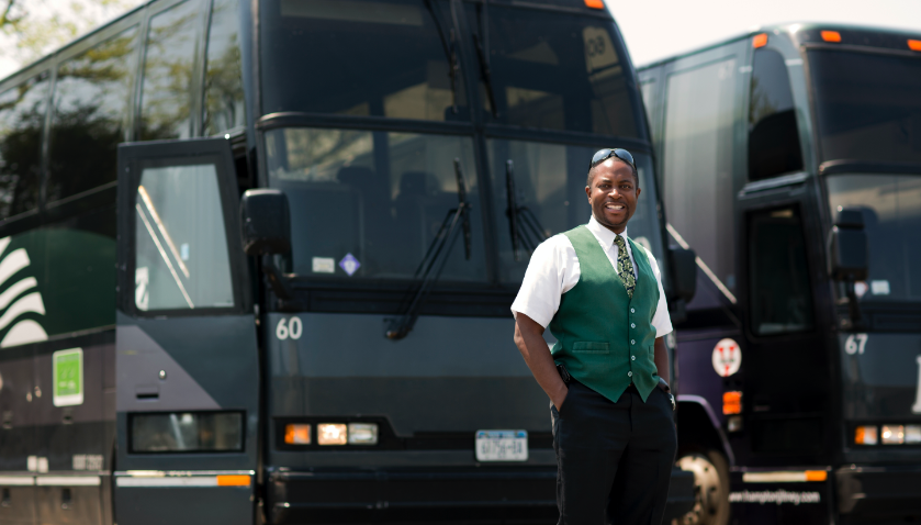 A confident men standing against two buses