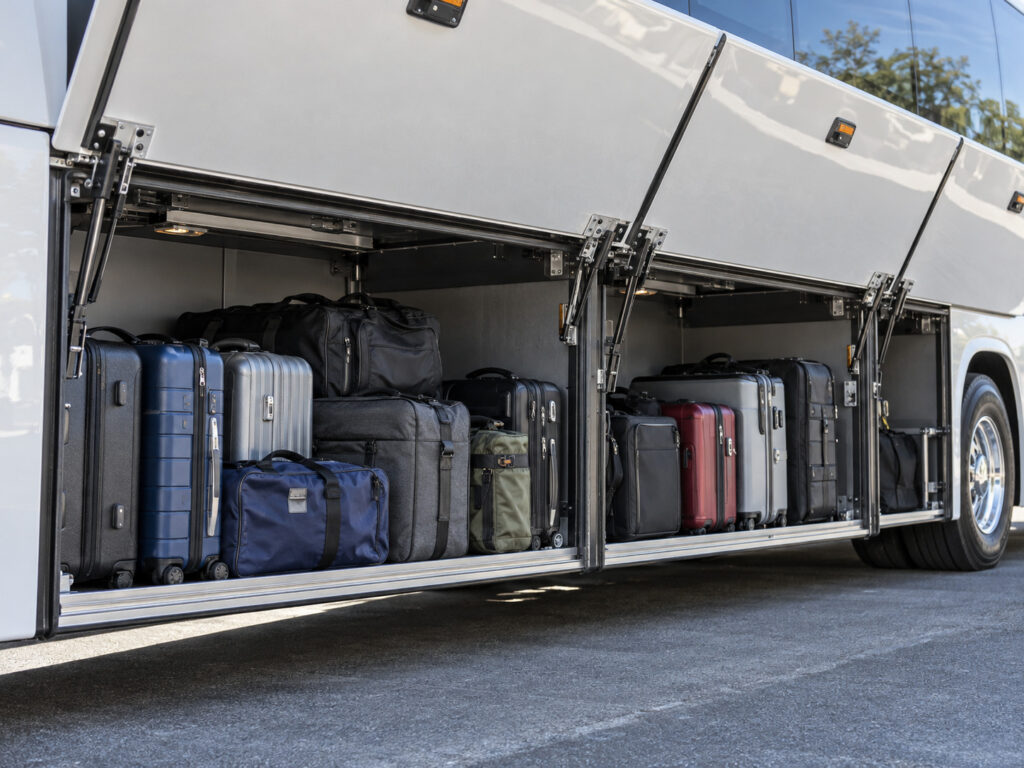 Suitcases loaded in the luggage compartment of a charter bus